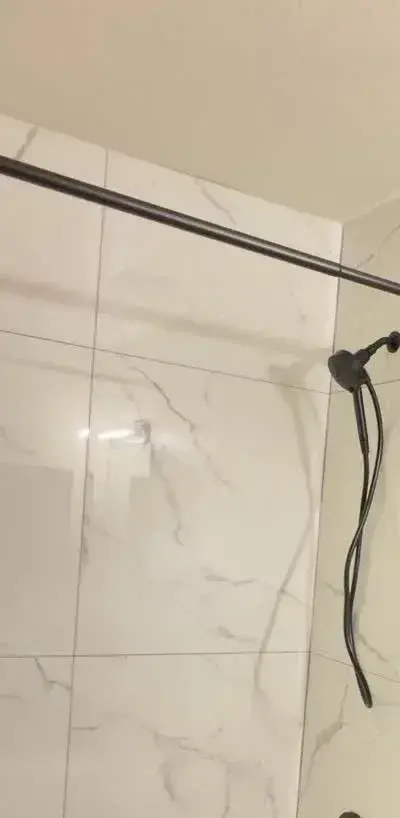 Marble-look tile shower with matte black fixtures by YG Reno